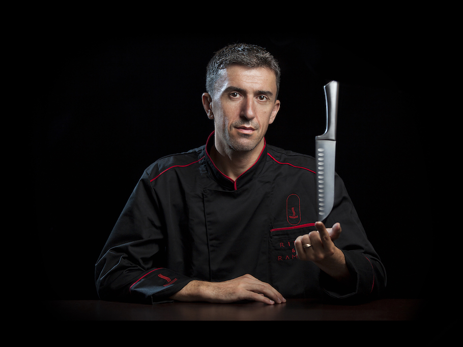 Portretul lui Mihai Pozderca, omul din spatele 'Ribs & Ranen', purtând tunica lui neagră de bucătar, decorată cu linii fine roșii și logoul 'Ribs & Ramen'.